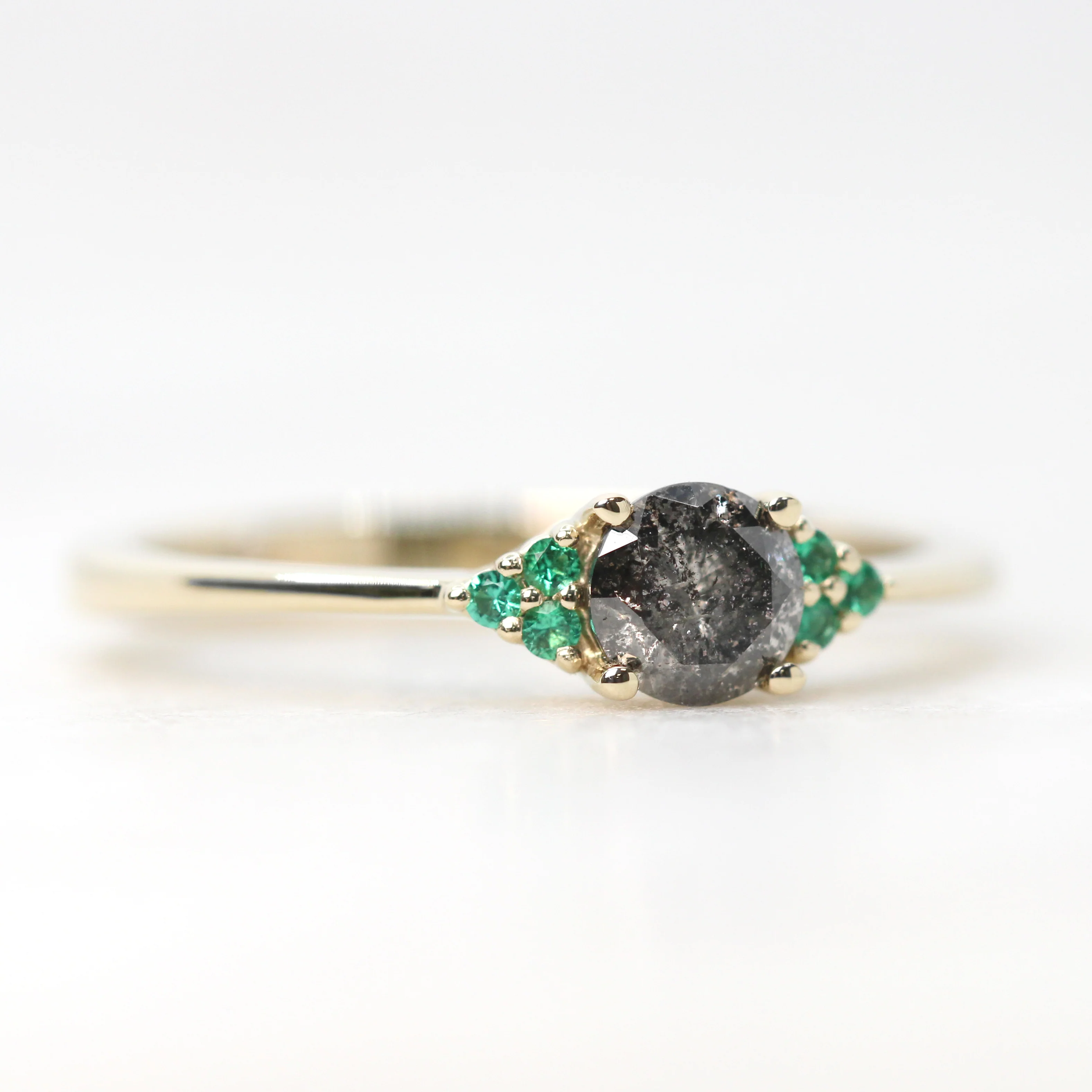 Project: Custom Imogene Ring with a 0.50 Carat Round Dark Gray Black Salt and Pepper Diamond and Emerald Accents in 14k - Image 5